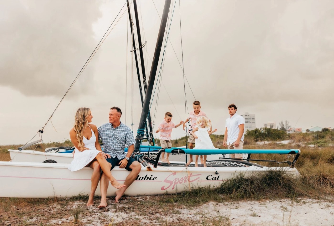BJ and his wife with their children gathered around a sailboat